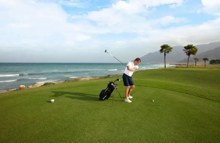 Jebel Sifah — golfer on the course by the sea